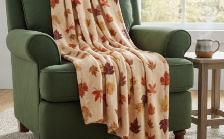 A custom fleece blanket in warm tones on an inviting armchair surrounded by autumn leaves.