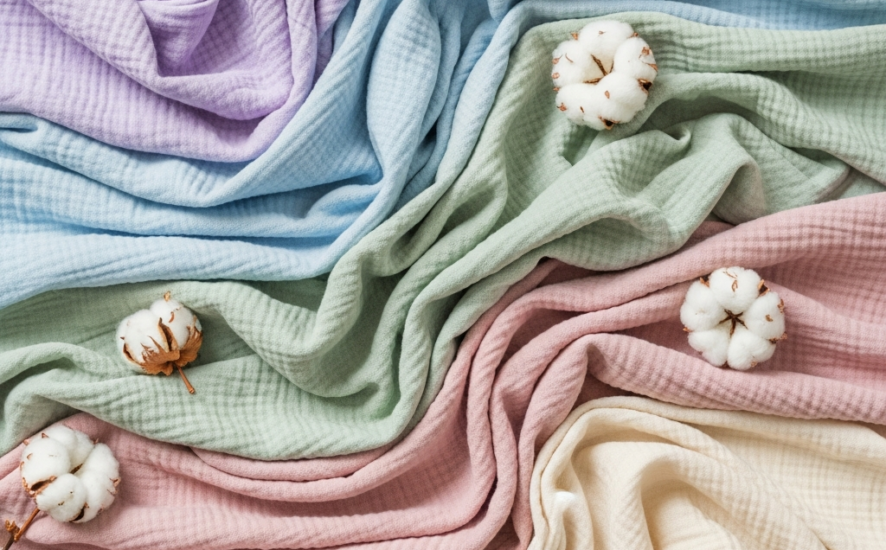 Flat lay of soft organic cotton fabrics in pastel colours.